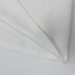 Detail view of the flatlock stitching and clean double-needle edge of white knit dress