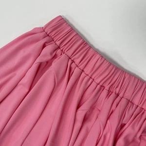 Macro detail of high-elasticity pleated waistband on pink resort-style skirt fabric