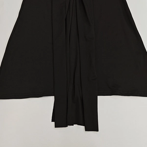 Detail view of black knit fabric with elegant draped pleats and neat hemline stitching