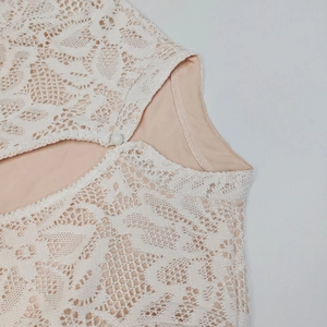 Dettaglio dell'abito in pizzo crochet bianco con fodera interna e bottone decorativo
