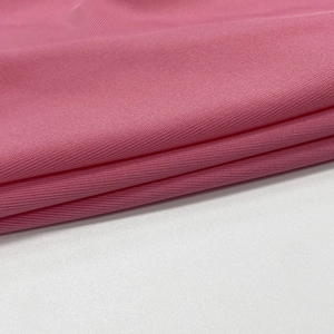 Close-up of peach pink knit fabric with fine texture for women's two-piece set