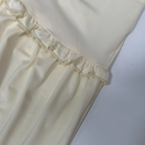 Gros plan détaillé du tissu en maille beige avec bords volantés et texture plissée élégante