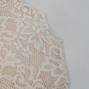 Dettaglio in pizzo floreale bianco con fodera nuda su abito elegante con maniche a campana
