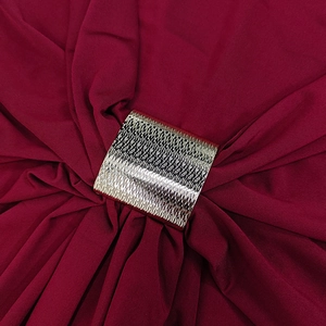 Macro shot of a square gold hammered metal buckle on a red textured knit dress