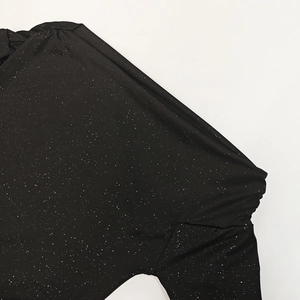 Close-up of black dress fabric with white shimmer spots and shoulder stitching detail