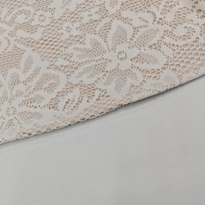 Dettaglio dell'intricato pizzo floreale bianco con fodera color nudo sul vestito