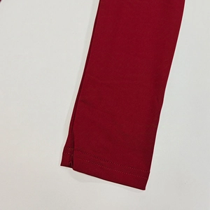 Detailed close-up of double-stitched hem on burgundy off-shoulder fitted dress