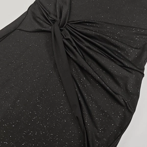 Close-up of black ruched dress fabric featuring silver glitter and twist detail