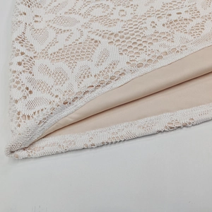 Dettaglio del tessuto in pizzo floreale bianco con fodera champagne sul vestito