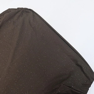Detail of dark brown off-shoulder sleeve with white glitter dots and ruched fabric texture