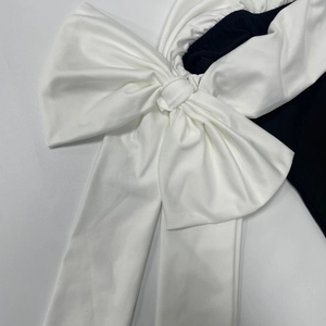 Détail d'un grand nœud papillon blanc en relief sur une robe moulante ajustée