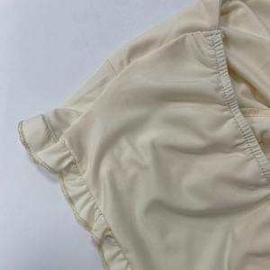 Détail du tissu ajouré ivoire avec bords élastiques à volants et coutures de précision