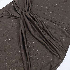 Detail of twist knot and pleated dark shimmering fabric with silver glitter finish