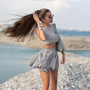 Close-up of light gray sleeveless crop top and pleated mini skirt set with belt detail