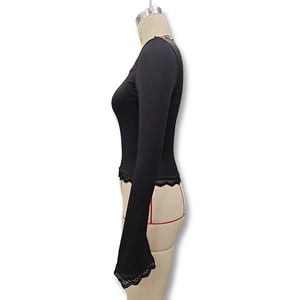 Close-up of black slim-fit top featuring delicate lace details on cuffs and hemline