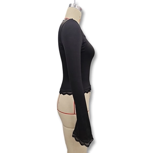 Detail view of black slim-fit top featuring delicate lace trim on cuffs and hemline