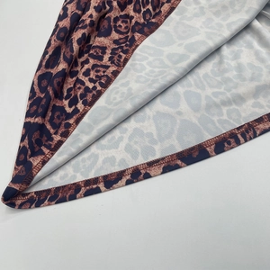 Détail de l'ourlet de la robe plissée léopard montrant la couture et le tissu