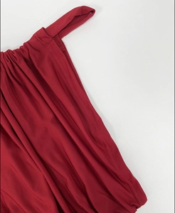 Detail of red knitted dress showing elastic fabric texture and double-needle stitching