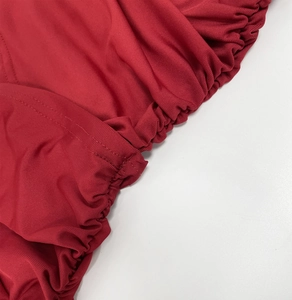 Detailed close-up of red ribbed knit fabric with elastic shirring and fine stitching