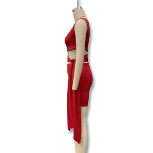 Detail view of red two-piece dress showing side cutout and long waist tie on mannequin