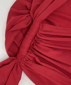 Detail of dark red dress showing intricate smocked texture and gathered ruched fabric