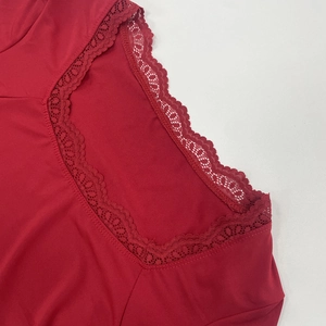 Detail of red V-neck top showing exquisite floral lace trim on deep red smooth fabric