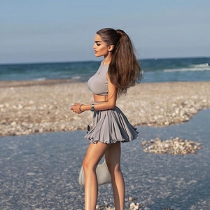 Detail of grey two-piece set featuring a backless crop top and pleated mini skirt