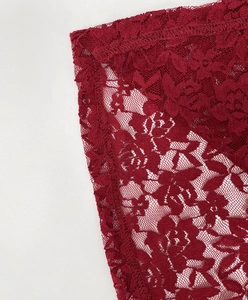 Macro detail of the elegant red lace dress showing intricate rose floral patterns and stitching