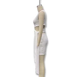 Detail of white two-piece bodycon set featuring a long side drape and slim-fit texture