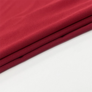 Macro shot of dark red ribbed knit fabric texture with fine vertical lines and soft folds