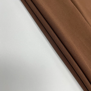 Détail de la texture du tissu en maille marron montrant le tissage lisse et le drapé du vêtement