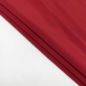 Macro shot of deep red knitted fabric with fine ribbed texture and elegant soft drape