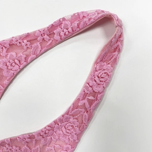 Vue macro de dentelle rose avec des motifs de roses et une structure en résille ajourée
