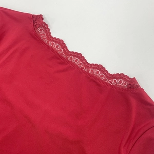 Detailed close-up of vibrant red top featuring elegant lace neckline and smooth knit fabric