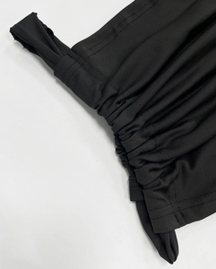 Macro shot of ruched black elastic knit fabric details on a sexy lace party dress