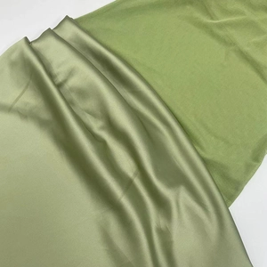 Close-up of sage green satin fabric texture and matte mesh detail for dresses