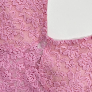 Gros plan sur le tissu en dentelle rose avec motifs floraux ajourés et couture soignée
