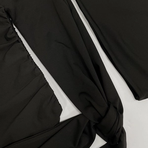 Close-up of black dress featuring pleated fabric details and decorative waist tie knots