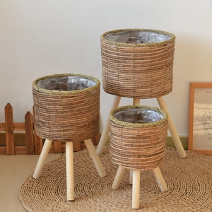 Three handwoven rattan plant stands with wood tripod legs and waterproof plastic liners