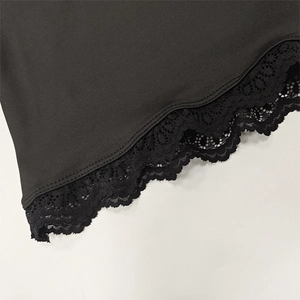 Detail of delicate black hollow lace hem on fitted knit top with intricate floral pattern