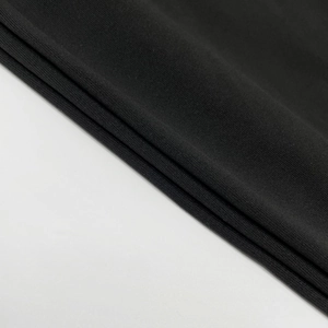 Detailed close-up showing the premium black knit fabric and fine lace texture of the dress