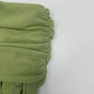 Close-up detail of light green ruched mesh fabric with breathable honeycomb texture