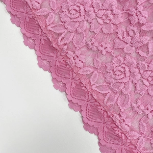 Gros plan sur un tissu en dentelle rose avec des motifs floraux de roses ajourés