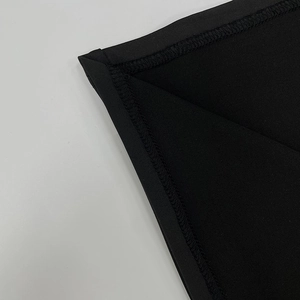 Détail rapproché des coutures surjetées professionnelles sur les bords du tissu noir tricoté