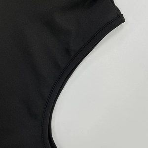 Gros plan sur le tissu en maille noire dense avec coutures précises sur une robe à capuche