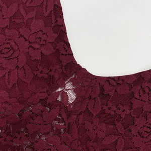 Gros plan sur un tissu en dentelle rouge foncé avec des motifs floraux et ajourés