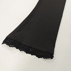 Detailed view of elegant black garment featuring delicate lace patchwork and flared cuffs