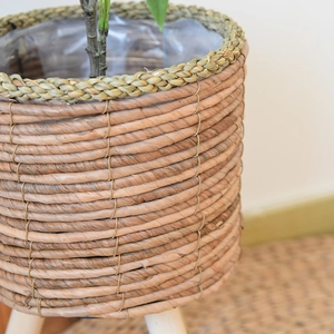Detail of hand-woven rattan planter featuring waterproof lining and natural wood legs