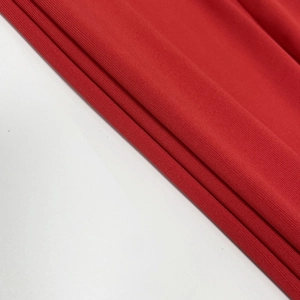 Close-up of the red knitted ribbed fabric texture and fine vertical stripes of the dress