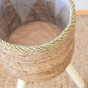 Detail of hand-woven rattan planter with solid wood tripod legs and waterproof liner
